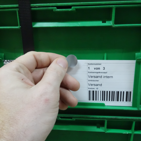 Klebepunkte G 19 werden mit Hand manuell auf VDA Label und auf den Ladungsträger geklebt